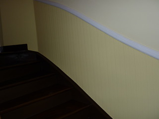 Treppe mit gelb tapezierter Wand und geschwungener Zierleiste – sauberes Tapezieren für ein harmonisches Treppenhausdesign.