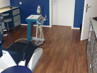 Zahnarztpraxis mit blau-weißer Einrichtung und robustem PVC-Boden in Holzoptik. Der Boden sorgt für eine warme Atmosphäre und ist zugleich pflegeleicht und hygienisch.